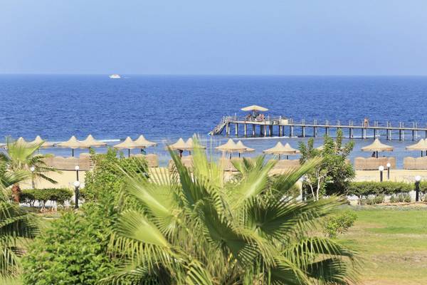 Aussicht auf das Drei Ecken Happy Leben Strand Resort mit Palmen, Strand und Pier im Hintergrund.