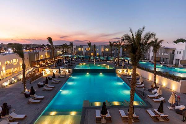 Abendlicher Poolbereich des Sunrise Royal Makadi Resorts mit leuchtenden Palmen und Liegen