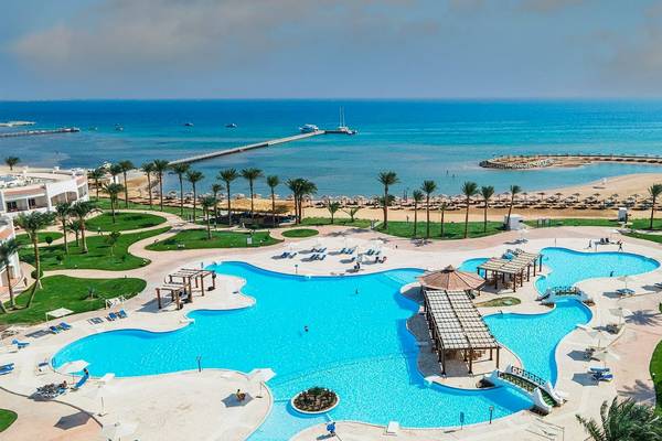 Luftaufnahme des Sunrise Royal Makadi Resorts mit Swimmingpool, Sonnenliegen und Blick aufs Meer.