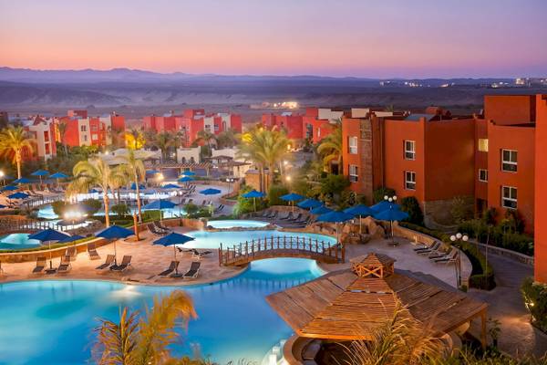 Luftaufnahme des Sunrise Royal Makadi Resorts mit Swimmingpools, Liegestühlen und roten Gebäuden.