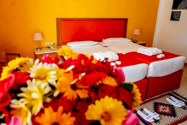 Doppelzimmer im Gorgonia Beach Resort mit zwei Betten, gelben und roten Blumen, und einem roten Kopfteil.