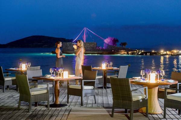 Zwei Frauen trinken auf der Terrasse des Elounda Beach Hotel bei Nacht.