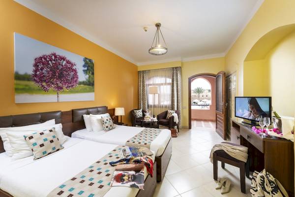 Doppelzimmer im Three Corners Rihana Resort mit zwei Betten, Fernseher und Möbeln.