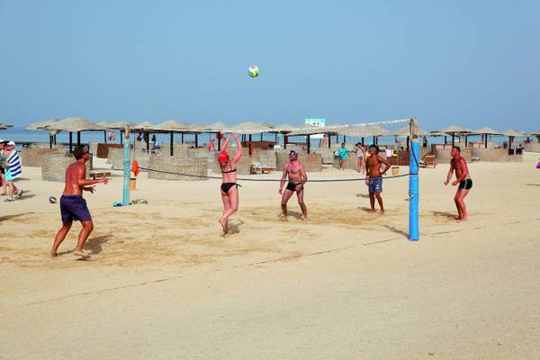 Mehrere Männer spielen Volleyball am Strand des Three Corners Fayrouz Plaza Beach Resort.