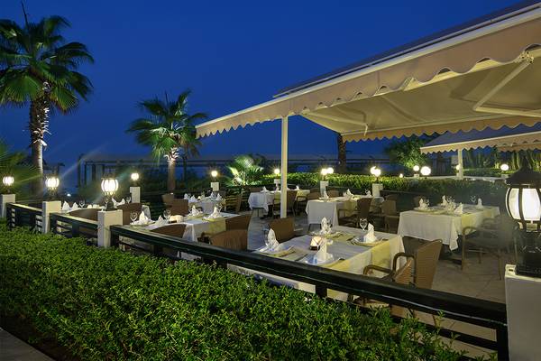 Restaurant des Crystal Family Resort & Spa bei Nacht mit beleuchteten Tischen und Palmen