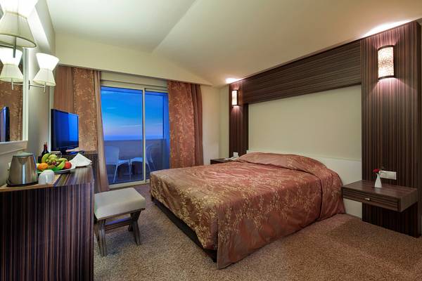 Innenansicht eines Hotelzimmers im Crystal Family Resort mit einem Doppelbett und einer Terrasse.