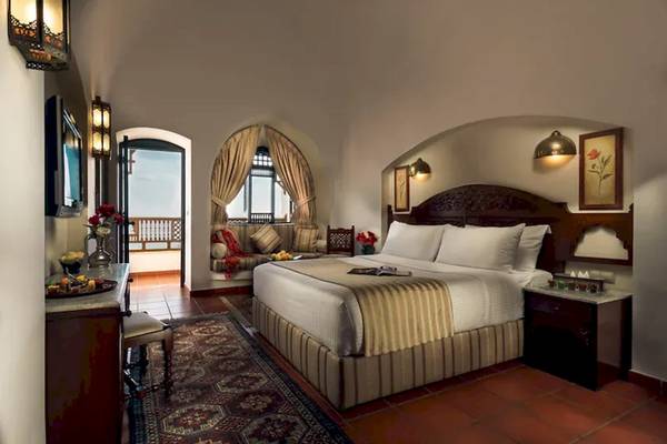 Innenansicht eines Suite-Zimmers im Mövenpick Resort Sharm el Sheikh mit einem großen Bett und einer gemütlichen Sitzecke.