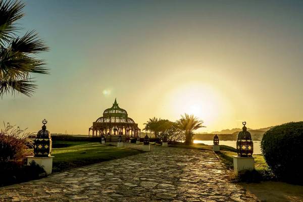 Sonnenuntergang am Mövenpick Resort Sharm el Sheikh mit einem Steinweg und Pavillon im Vordergrund.