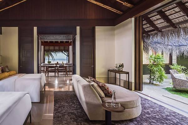 Innenansicht der Suite im One & Only Reethi Rah Hotel mit zwei Betten und einem Wohnzimmer.