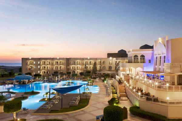Abendliche Sicht auf das Wyndham Garden Salalah Mirbat Hotel mit Swimmingpool und Terrasse.