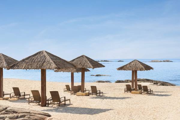 Strand des Wyndham Garden Salalah Mirbat mit Liegen unter Strohdächern