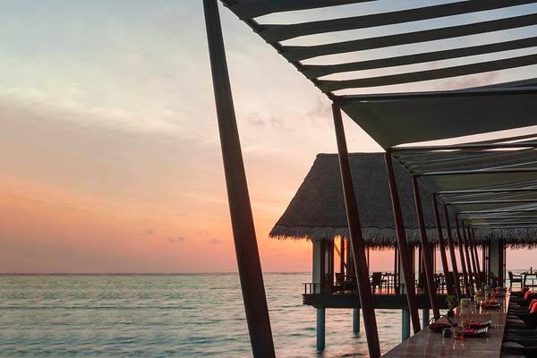 Terrasse des One & Only Reethi Rah Hotels bei Sonnenuntergang mit Blick auf das Meer.
