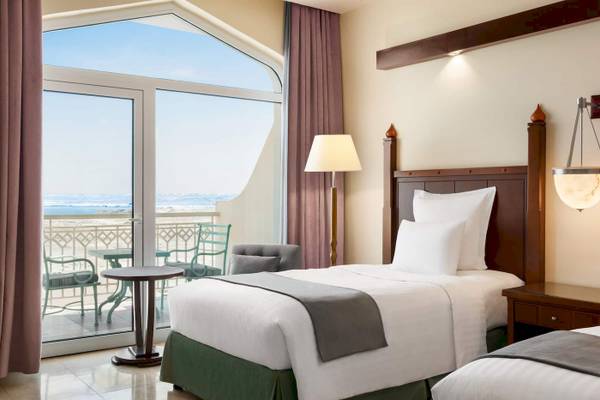 Zimmer im Wyndham Garden Salalah Mirbat Hotel mit Blick auf das Meer von einem Balkon.