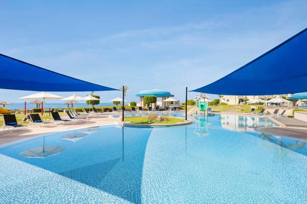 Außenpool des Wyndham Garden Salalah Mirbat Hotels mit Lounge-Stühlen und Sonnenschirmen
