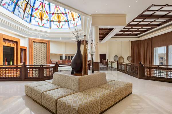 Empfangshalle des Wyndham Garden Salalah Mirbat mit Sitzecke, Vasen und buntem Glasdach