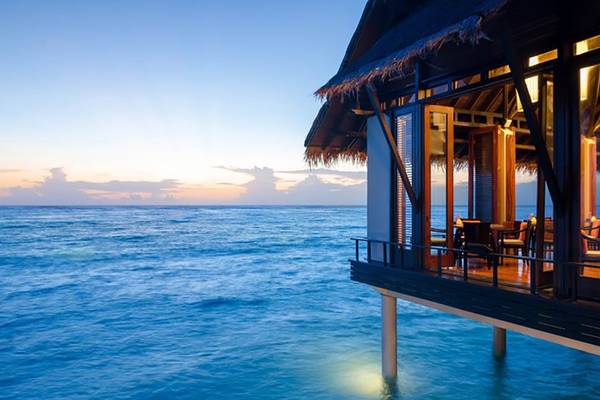 Außenterrasse des One & Only Reethi Rah mit Blick auf das Meer während des Sonnenuntergangs.