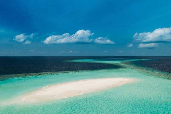 Luftaufnahme des One & Only Reethi Rah Hotels, das auf einer weißen Sandbank im Ozean liegt.