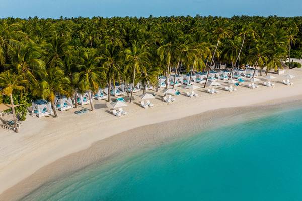 Luftaufnahme des One & Only Reethi Rah Strandes mit weißen Sonnenliegen und Sonnenschirmen.