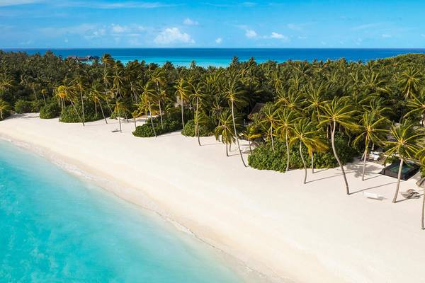 Ein tropischer Strand mit weißen Palmen und blauem Wasser am One & Only Reethi Rah