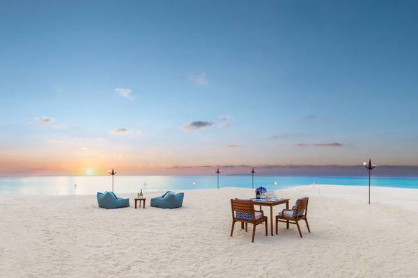 Strand des One & Only Reethi Rah mit Sonnenuntergang im Hintergrund