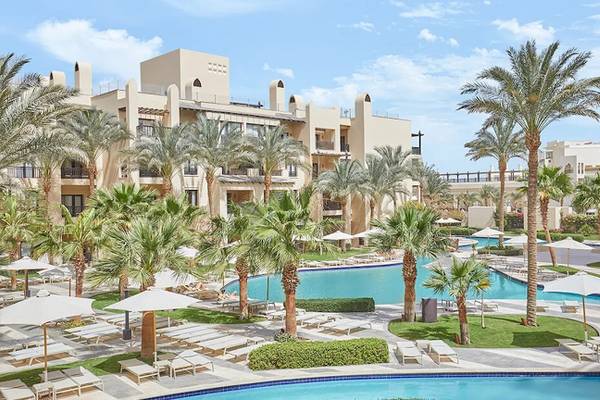 Außenbereich des Steigenberger Aqua Magic Resorts mit Pool, Palmen und Liegestühlen.