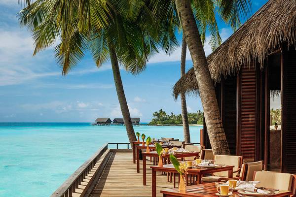Außenterrasse des One & Only Reethi Rah mit Blick auf das Meer und Palmen.