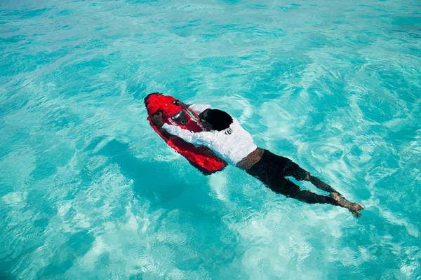 Person schwimmt im blauen Wasser mit roter Ausrüstung