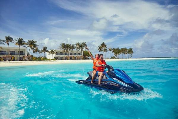 Zwei Leute auf einem Jetski vor dem RIU Atoll Hotel.