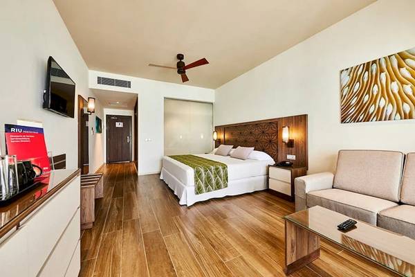 Hotelzimmer im RIU Atoll mit Bett, Couch, Tisch und Fernseher.