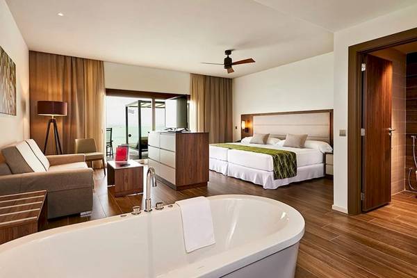 Innenansicht einer Suite im RIU Atoll Hotel mit Badewanne, Sofa, Schreibtisch und Schlafzimmer.
