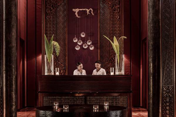 Innenansicht der Rezeption des One & Only Reethi Rah Hotels mit zwei Mitarbeitern und dekorativen Elementen.