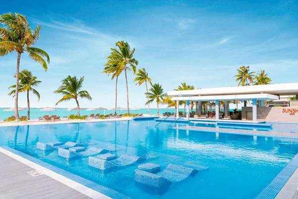 Außenpool des RIU Atoll Hotels mit Sonnenliegen und Palmen am Strand