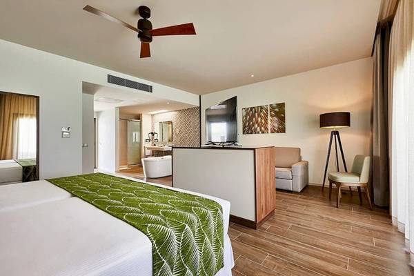 Ein luxuriöses Zimmer im RIU Atoll Hotel mit einem großen Bett, einer Couch und einem Fernseher.