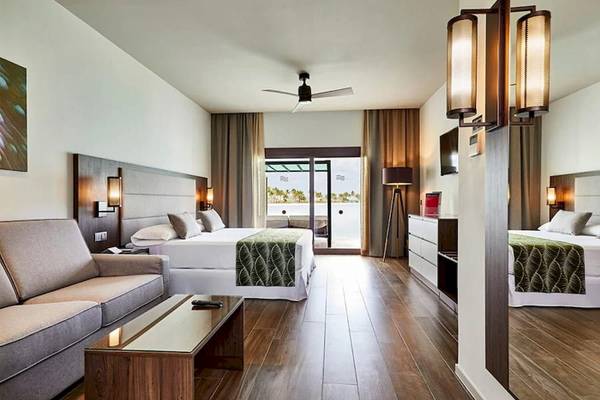 Ein luxuriöses Zimmer im RIU Atoll Hotel mit einem großen Bett, einer Couch und einem Fernseher.
