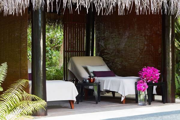 Massage-Lounge im Freien mit zwei Liegen und Blumenvase im Hotel One & Only Reethi Rah