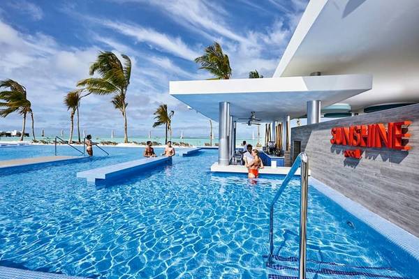 Außenpool des RIU Atoll Hotels mit Sonnenliegen und Palmen am Strand