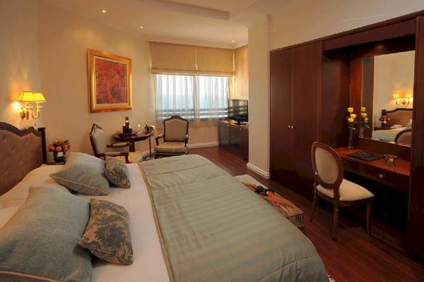 Hotelzimmer von Alexander The Great mit Bett, Sesseln und Schreibtisch.