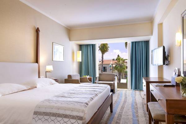 Hotelzimmer von Alexander The Great mit Bett, Sessel, Schreibtisch und Fernseher.