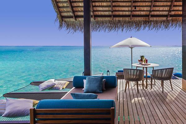 Außenterrasse des One & Only Reethi Rah mit Blick auf das Meer, Sonnenschirm und Möbeln