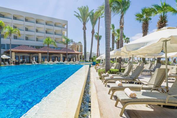 Pool im Alexander The Great Hotel mit Palmen und Sonnenliegen