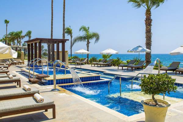Pool im Alexander The Great Hotel mit Palmen und Sonnenliegen