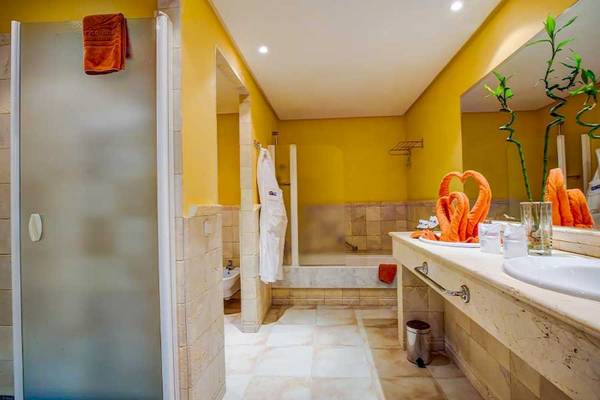 SBH Hotel Costa Calma Palace Badezimmer mit gelben Wänden, Badewanne, Handtüchern und Waschbecken.