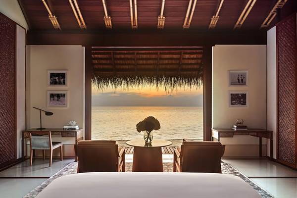 Ein Zimmer im One & Only Reethi Rah mit Meerblick bei Sonnenuntergang.