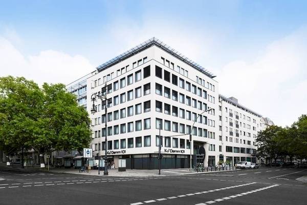 Außenansicht des Ku Damm 101 Hotels, ein modernes weißes Gebäude mit vielen Fenstern.