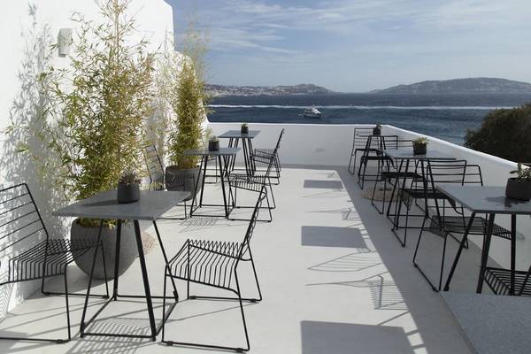 Moderne Terrasse mit Tischen, Stühlen und Meerblick