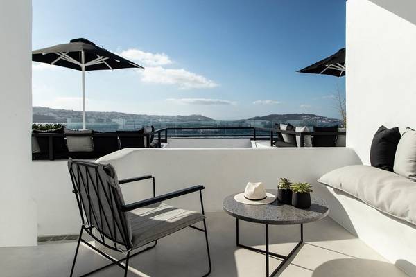 Terrasse mit Blick auf das Meer und Berge, ausgestattet mit Stühlen, Tisch und Sonnenschirmen