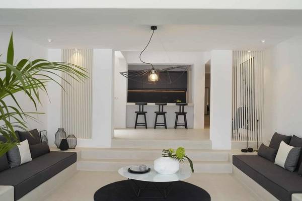 Moderner Lounge-Bereich im Nimbus Hotel mit dunklen Sofas, einem runden Tisch und einer Bar im Hintergrund.