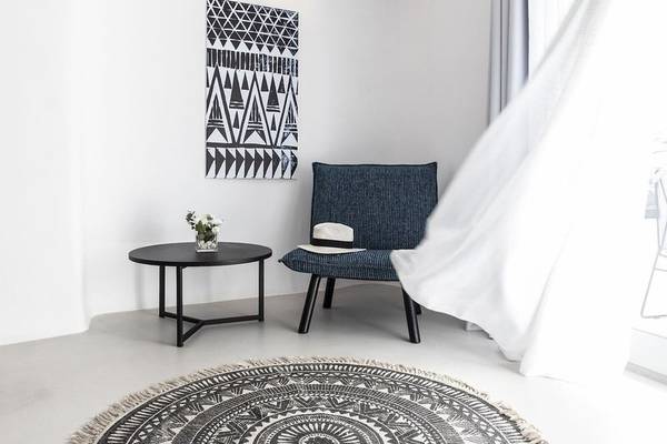 Moderner Raum im Nimbus Hotel mit grauer Couch, schwarzem Tisch und dekorativem Kunstwerk