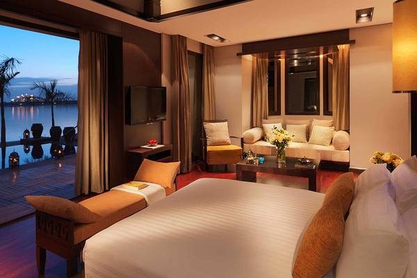 Zimmer im Anantara The Palm Dubai Resort mit Aussicht auf den See und die Stadt bei Nacht.