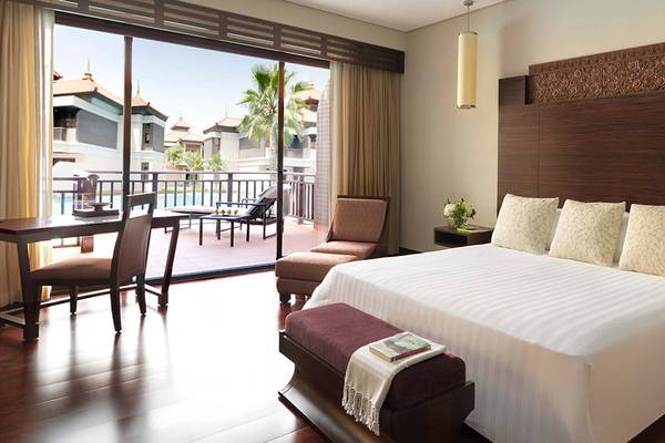 Schlafzimmer im Anantara The Palm Dubai Resort mit einem großen Bett, Balkon und Aussicht auf den Pool.